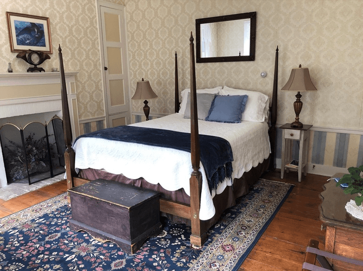 A cozy bedroom featuring a four-poster bed, a wooden chest, and decorative lamps on side tables.